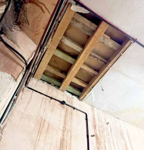 Exposed services and joists across a damaged ceiling