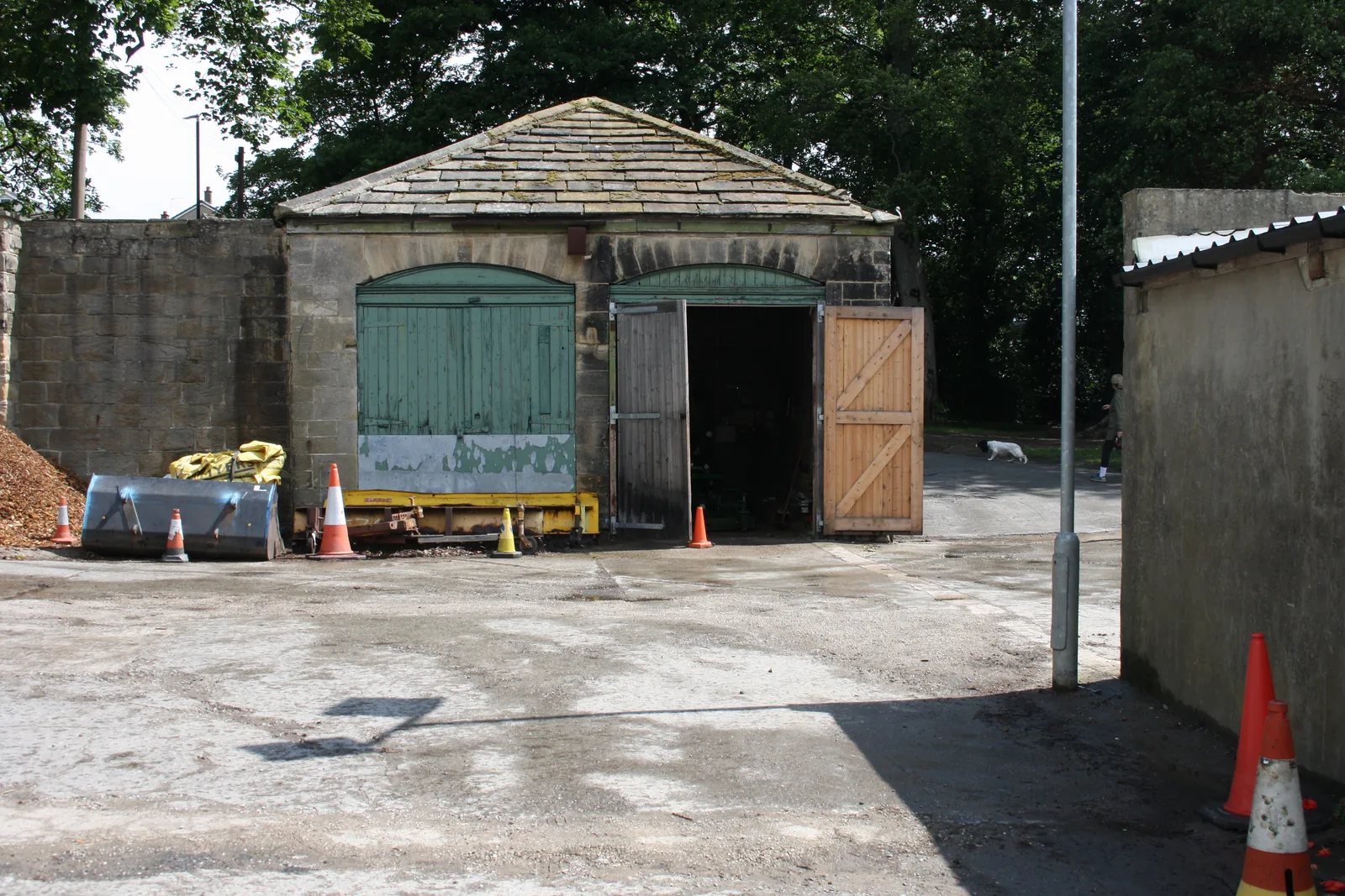 The coach house with its hipped stone roof and arched timber doors